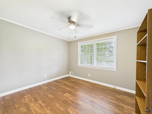 spare room with baseboards, dark wood finished floors, and crown molding