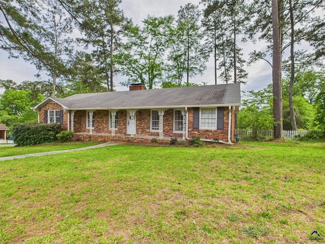 ranch-style home with fence, a chimney, a front lawn, and brick siding
