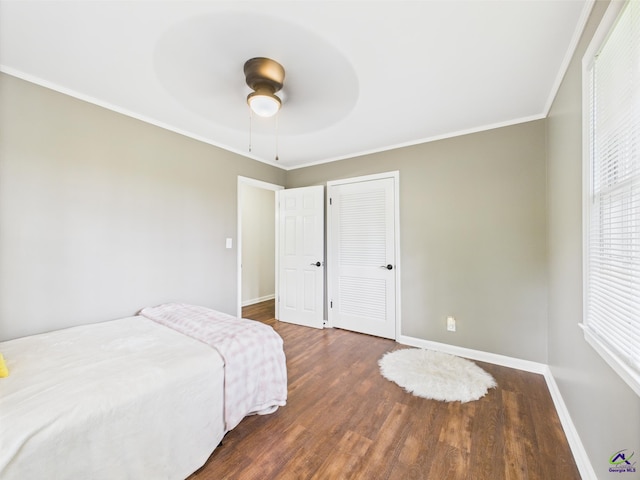 bedroom with baseboards, ornamental molding, wood finished floors, and a closet