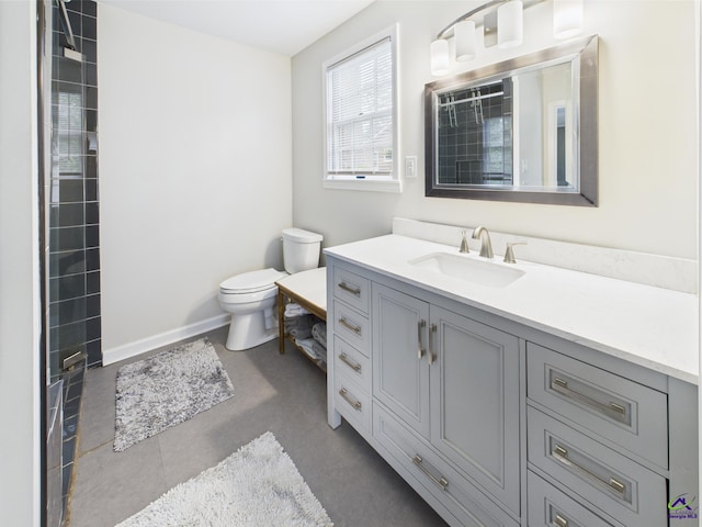 full bath with tile patterned flooring, vanity, toilet, baseboards, and tiled shower