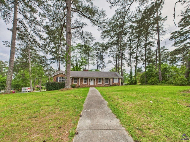 single story home featuring brick siding, a front yard, and a chimney