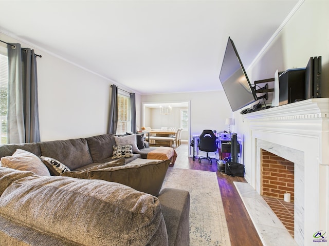 living room featuring ornamental molding, a fireplace, wood finished floors, and a chandelier