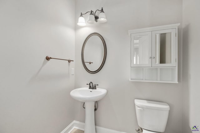 half bath featuring baseboards and toilet