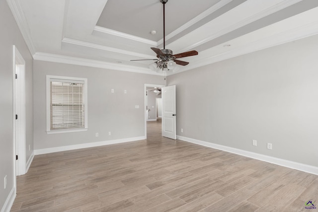 unfurnished bedroom with crown molding, ceiling fan, light wood finished floors, baseboards, and a tray ceiling
