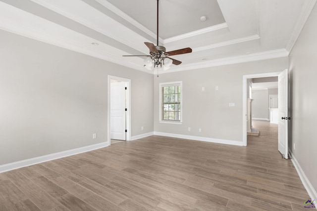empty room featuring baseboards, a ceiling fan, wood finished floors, and a tray ceiling