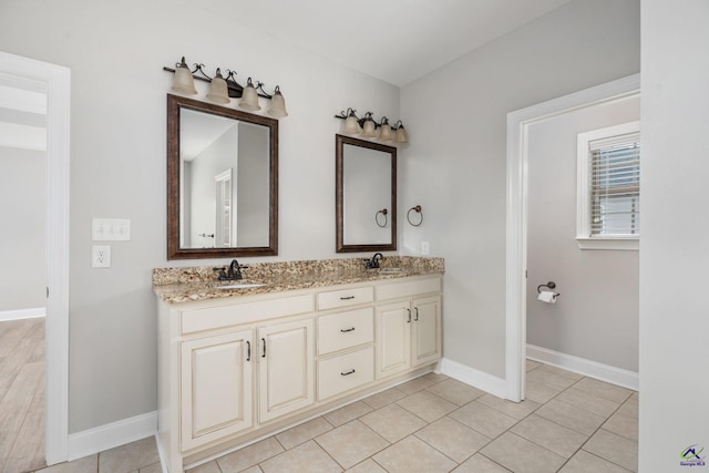 full bath featuring double vanity, baseboards, a sink, and tile patterned floors