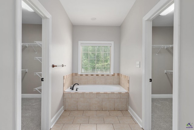 bathroom featuring a garden tub, a walk in closet, and tile patterned flooring