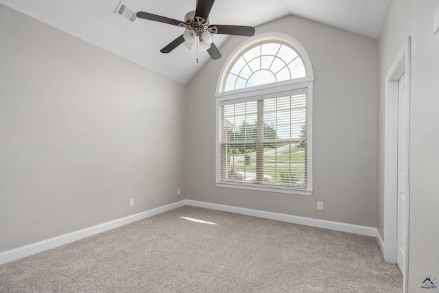 carpeted empty room featuring plenty of natural light, a ceiling fan, visible vents, and vaulted ceiling