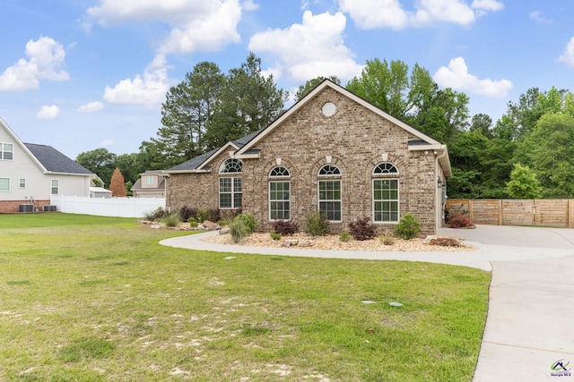 view of front of home featuring fence, cooling unit, a front yard, and brick siding