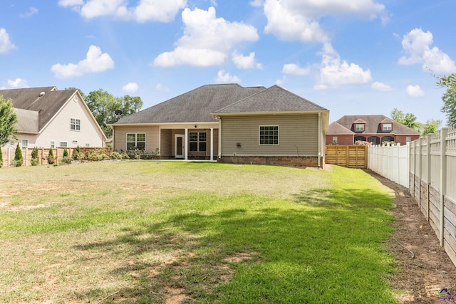 rear view of property with a lawn and a fenced backyard