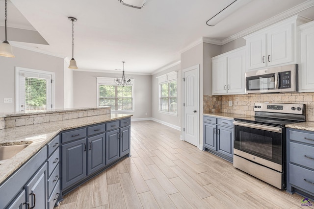 kitchen featuring an inviting chandelier, baseboards, white cabinets, appliances with stainless steel finishes, and backsplash