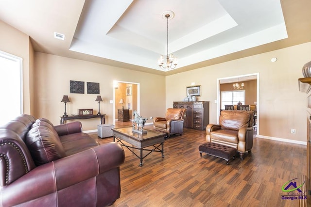 living room with visible vents, a chandelier, and a raised ceiling