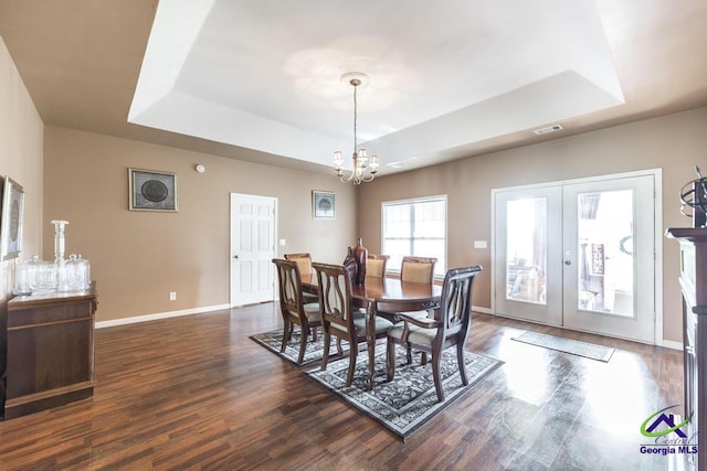 dining room with a notable chandelier, baseboards, a tray ceiling, visible vents, and dark wood-style floors