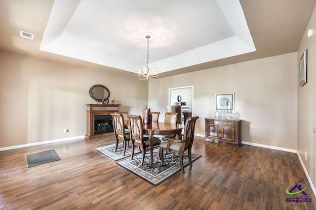 dining space with visible vents, an inviting chandelier, a raised ceiling, and wood finished floors