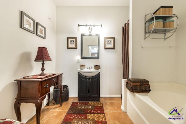 bathroom with vanity, tile patterned flooring, baseboards, and a bath