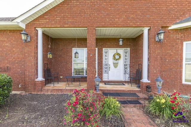 property entrance with a porch and brick siding