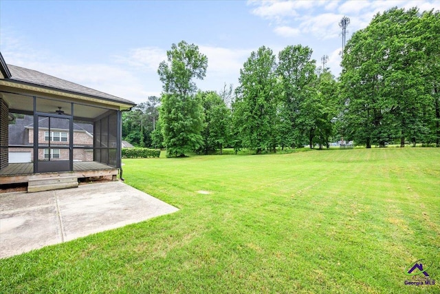 view of yard with a ceiling fan, a patio area, and a sunroom