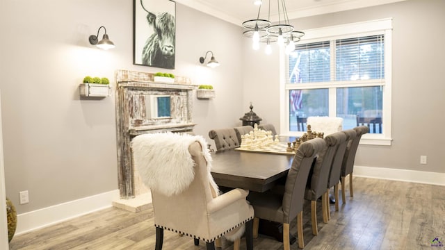 dining room featuring ornamental molding, baseboards, a notable chandelier, and wood finished floors