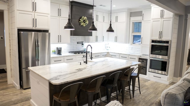 kitchen featuring white cabinetry, backsplash, light wood finished floors, and appliances with stainless steel finishes