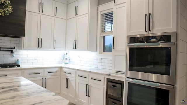 kitchen featuring double oven, white cabinets, and decorative backsplash