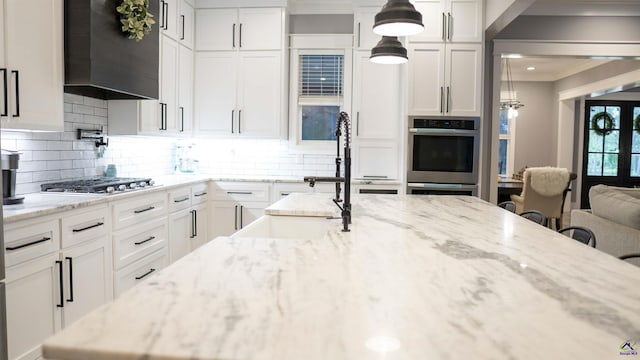 kitchen featuring stainless steel appliances, white cabinets, and wall chimney exhaust hood