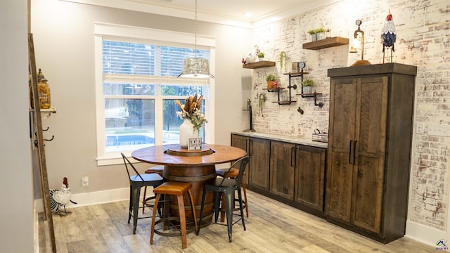 dining room featuring crown molding, light wood-style flooring, baseboards, and a healthy amount of sunlight