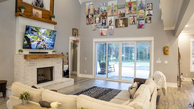 living room with a fireplace, a high ceiling, baseboards, and wood finished floors