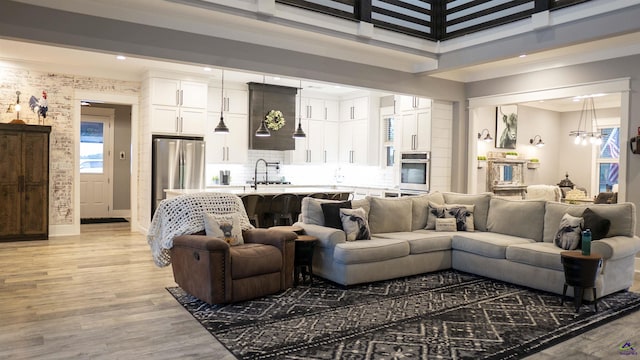 living room featuring light wood finished floors, baseboards, a high ceiling, and recessed lighting