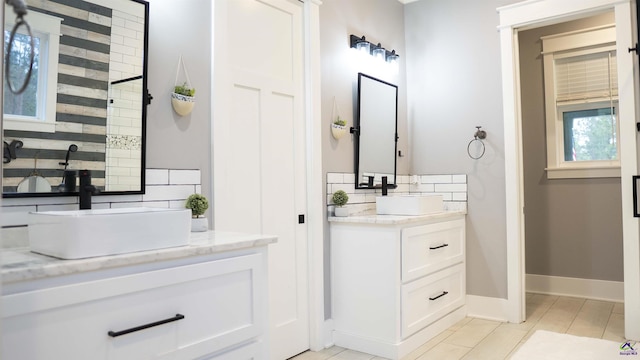 full bath with vanity, tasteful backsplash, baseboards, and tile patterned flooring