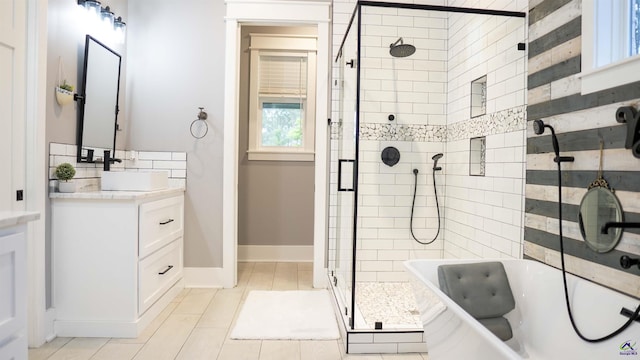 full bath featuring a stall shower, tile patterned floors, a bath, baseboards, and vanity