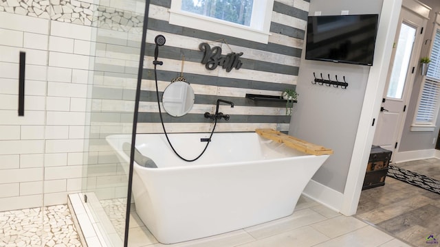 bathroom with a soaking tub, baseboards, and walk in shower