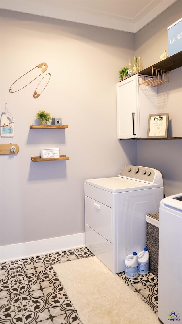 laundry area featuring cabinet space, washing machine and clothes dryer, and baseboards