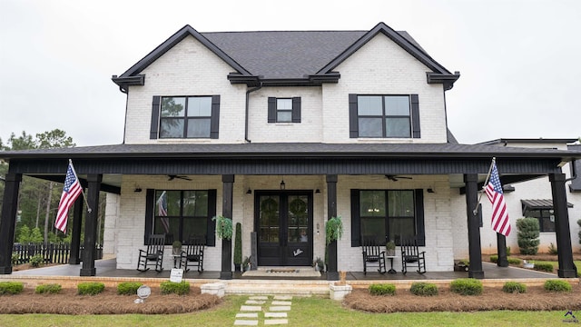 modern farmhouse style home with a ceiling fan, french doors, brick siding, and covered porch
