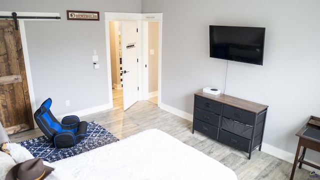 bedroom with baseboards, a barn door, and wood finished floors