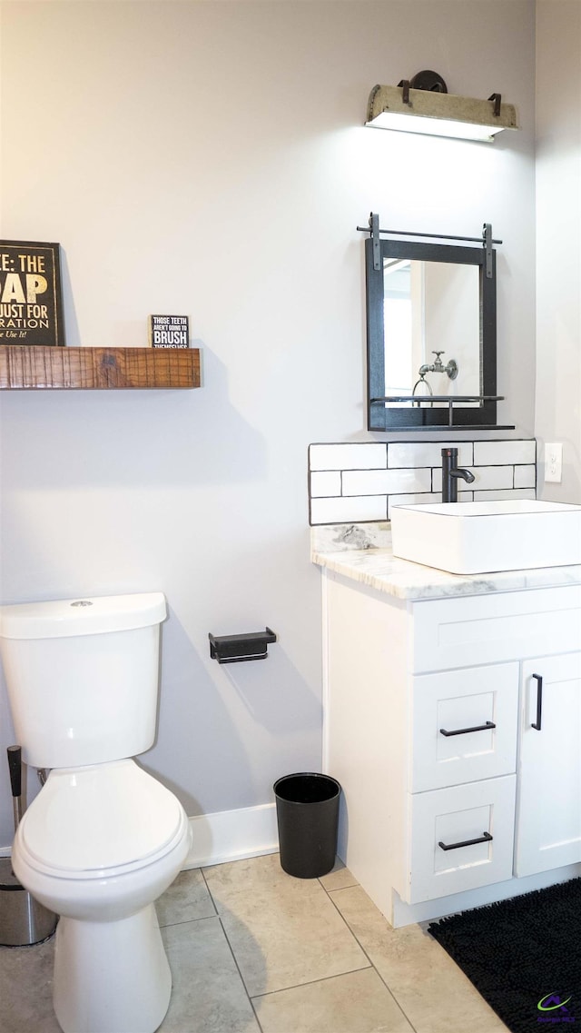 half bath featuring vanity, toilet, baseboards, and tile patterned floors