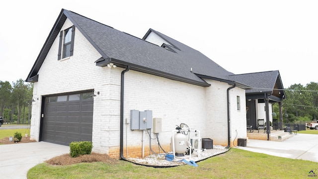 view of side of home featuring driveway, roof with shingles, brick siding, and an attached garage