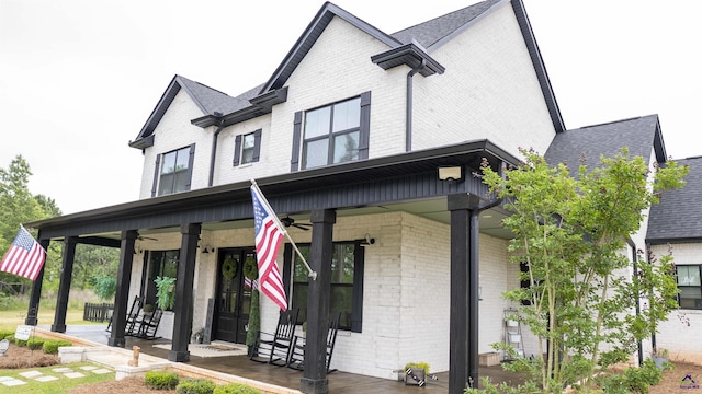 view of front of house with a ceiling fan, a shingled roof, brick siding, and covered porch