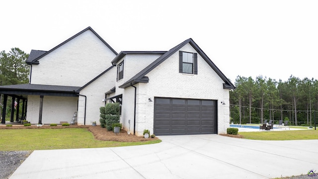 view of front of home featuring brick siding, an outdoor pool, driveway, a garage, and a front lawn