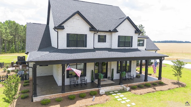 view of front of house featuring a front yard, a porch, brick siding, and a shingled roof