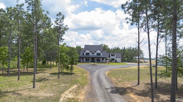 view of front facade with dirt driveway and a front yard