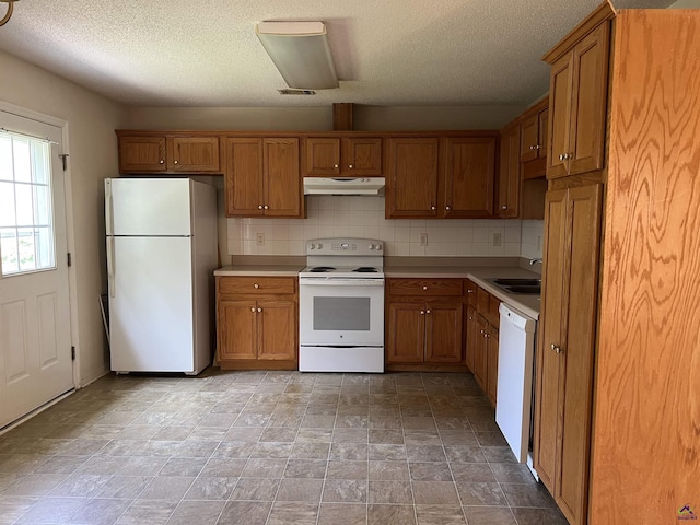 113 Easy St, Dublin, GA 31021 - kitchen featuring white appliances, under cabinet range hood, brown cabinets, a sink, and a textured ceiling