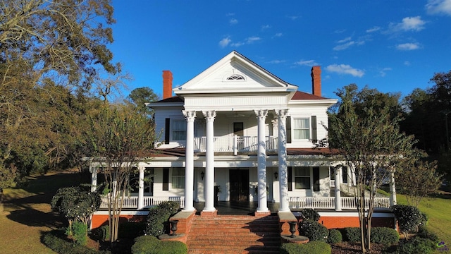 neoclassical / greek revival house with a porch, a chimney, and a balcony