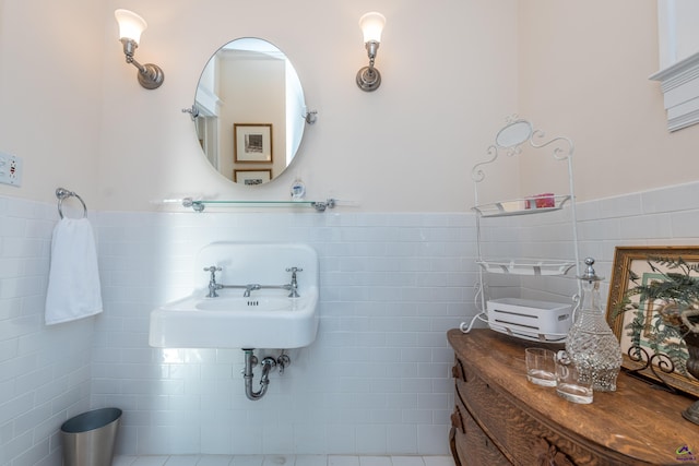 bathroom with a sink, tile walls, and a wainscoted wall