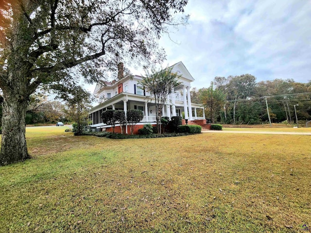 view of front of house with a porch, a chimney, and a front yard