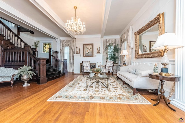 living area with stairway, an inviting chandelier, crown molding, and wood finished floors