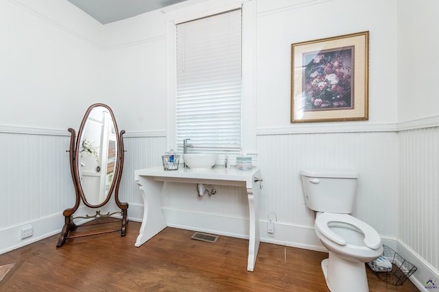 bathroom with toilet, visible vents, wood finished floors, and wainscoting
