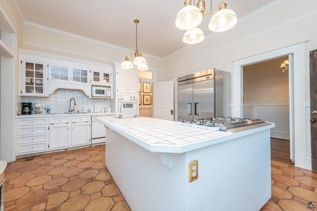 kitchen with an inviting chandelier, white appliances, tile countertops, and a center island