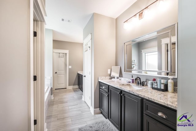 217 Woodlands Blvd, Kathleen, GA 31047 - bathroom with vanity, wood finished floors, a tub, and baseboards