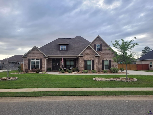 craftsman-style home with a front yard, brick siding, and fence