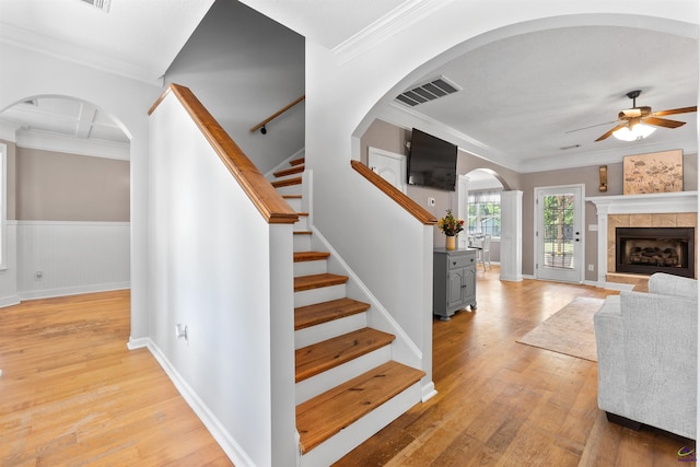stairway with ceiling fan, crown molding, visible vents, and wood finished floors